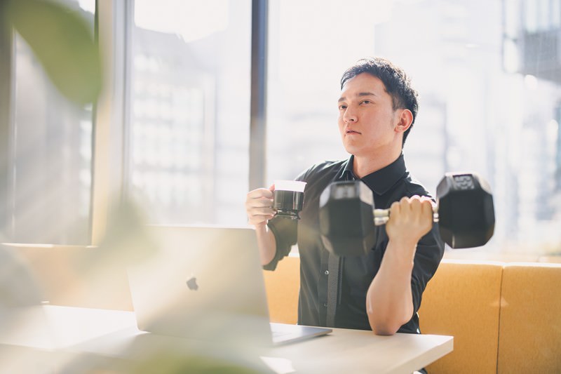 コーヒーを飲みながらダンベルで鍛えてるの図